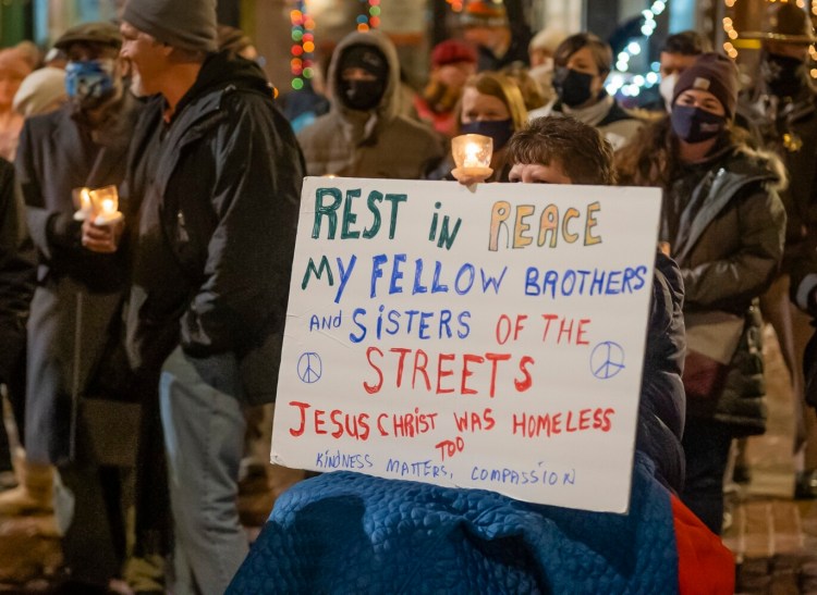 A woman conveys her thoughts with a sign during the gathering Tuesday in Monument Square to remember those who died while homeless this year.