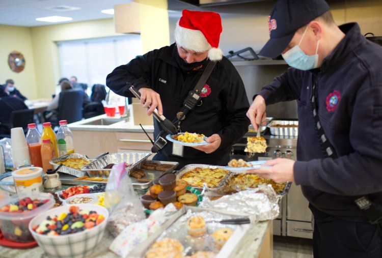 South Portland firefighters Lt. Seth Hagar and Capt. Jon Martin, right, dig into a Christmas brunch that was delivered to Cash Corner station on Christmas morning. 
