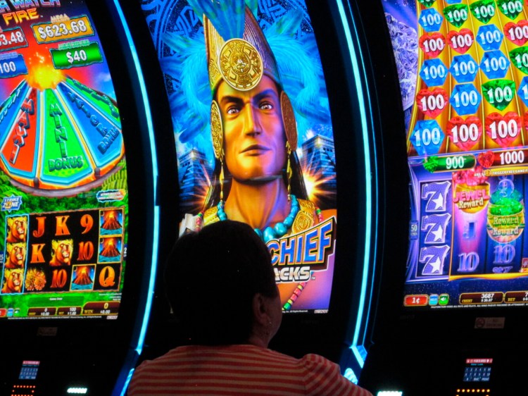 This June 23, 2021, photo shows a gambler playing a slot machine at Bally's casino in Atlantic City, N.J. Several casinos are forging ahead with significant investment and renovation projects in 2022, even as the coronavirus pandemic continues to make it harder to do business. (AP Photo/Wayne Parry)