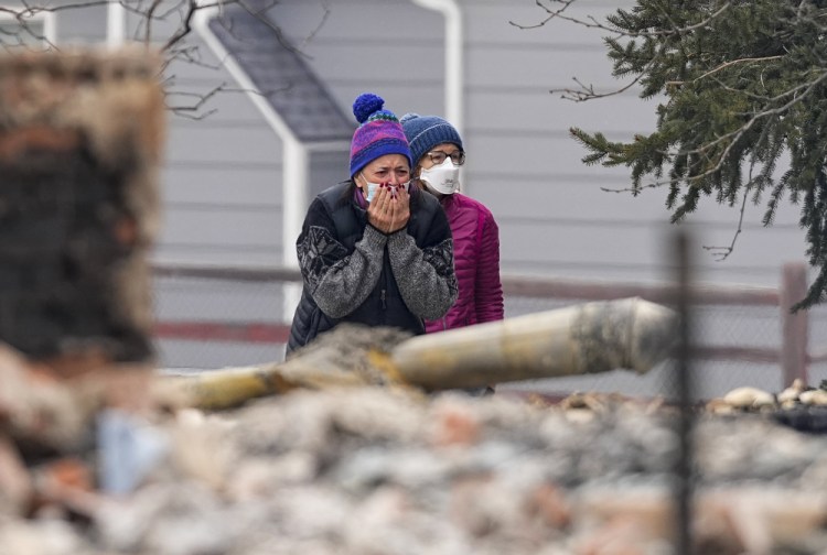 A woman cries upon seeing the burned remains of a home destroyed by the Marshall Wildfire in Louisville, Colo., on Friday. (AP Photo/Jack Dempsey)