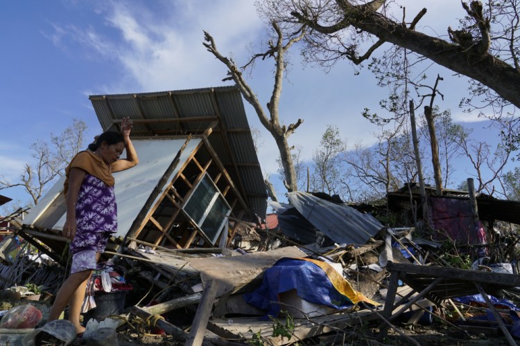A resident salvages parts of her home damaged by Typhoon Rai in Talisay, Cebu province, central Philippines on Saturday. More than 300,000 villagers had fled to safety before the onslaught, officials said. 

