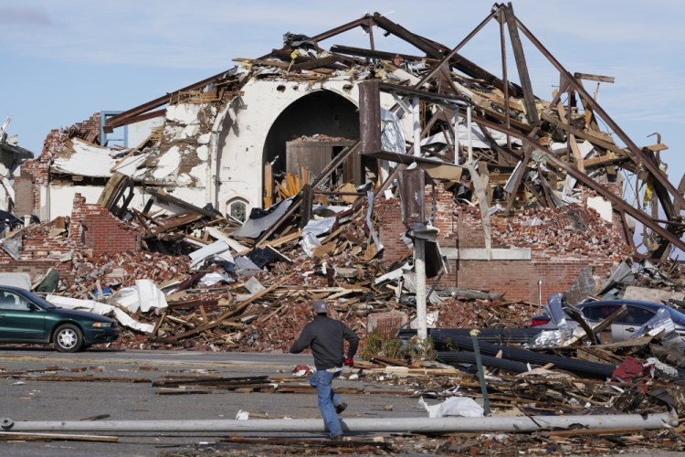 People survey damage from a tornado in Mayfield, Ky., on Saturday. Tornadoes and severe weather caused catastrophic damage across multiple states late Friday, killing at least 70 people.