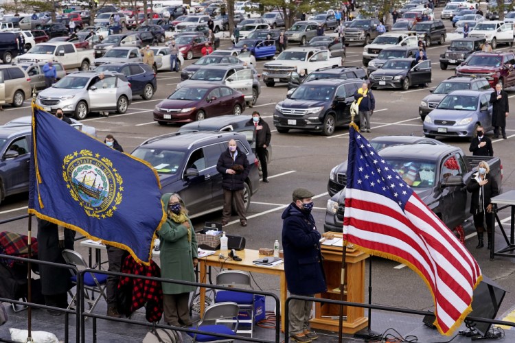State Representatives stand for the Pledge of Allegiance during an outdoor meeting of the New Hampshire House of Representatives in a parking lot on Jan. 6, 2021.