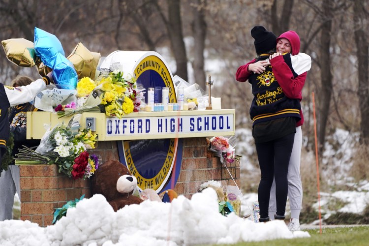 Students hug at a memorial at Oxford High School in Oxford Township, Mich., on Dec. 1. A 15-year-old student charged with killing four peers was allowed to remain in school despite troubling behavior.

