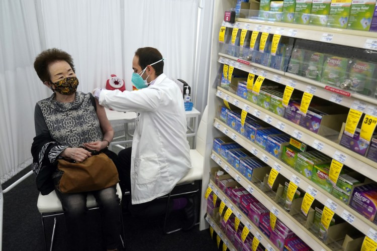 Pharmacist Todd Gharibian administers a dose of the Moderna COVID-19 vaccine to Toshiko Sugiyama at a CVS Pharmacy branch in Los Angeles. 