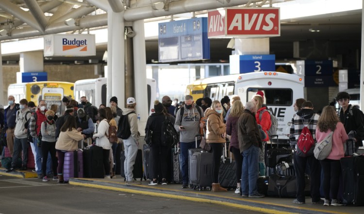 Travelers queue up for shuttle buses to rental car lots at Denver International Airport on Sunday. 