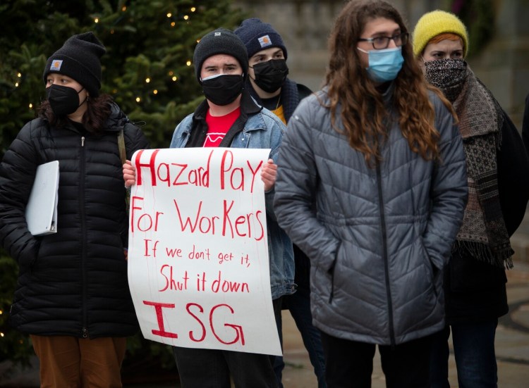 Emery Adams of Portland, a member of the Independent Socialist Group, holds a sign at an emergency rally for hazard pay, organized by Maine chapter of the Democratic Socialists of America at Portland’s city hall on Sunday. 