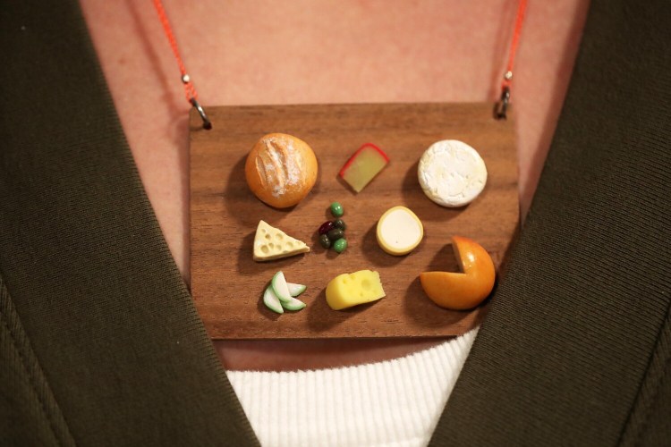Eat a cheese board, or maybe wear one. Artist Louisa Donelson wears one of her own creations, a micro sculpture of a cheese board she's fashioned into a necklace. Donelson is a painter, who also crafts tiny, hyper realistic food sculptures that she turns into jewelry. She wants people to enjoy wearing these but also hopes they spark connection and serious conversations about food.