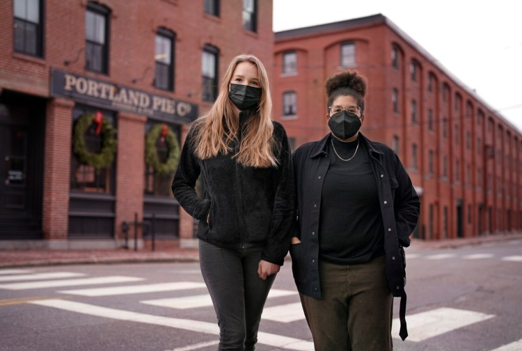 Server Olivia Crowley, left, and bartender Lauren Saxon stand in front of Portland Pie Co. in Portland on Monday. Crowley and Saxon are speaking out against what they say are a lack of coronavirus measures at the restaurant.