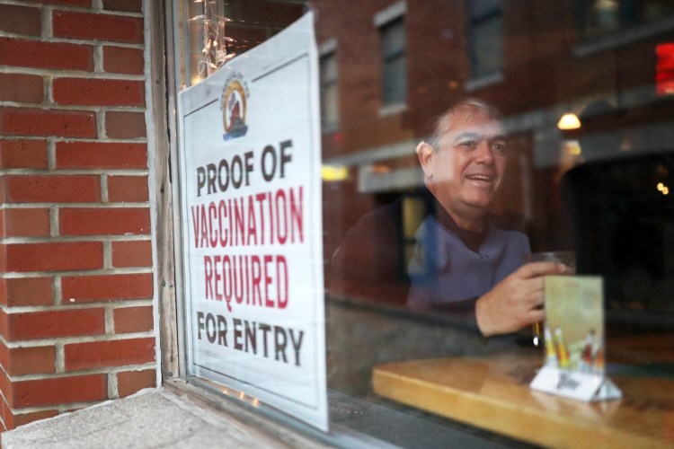 Colin McLean of Birmingham, Alabama, drinks a beer at a window seat at the Commercial Street Pub in Portland on Wednesday. The bar now requires proof of vaccination for entry, so it's exempt from Portland's new mask mandate.