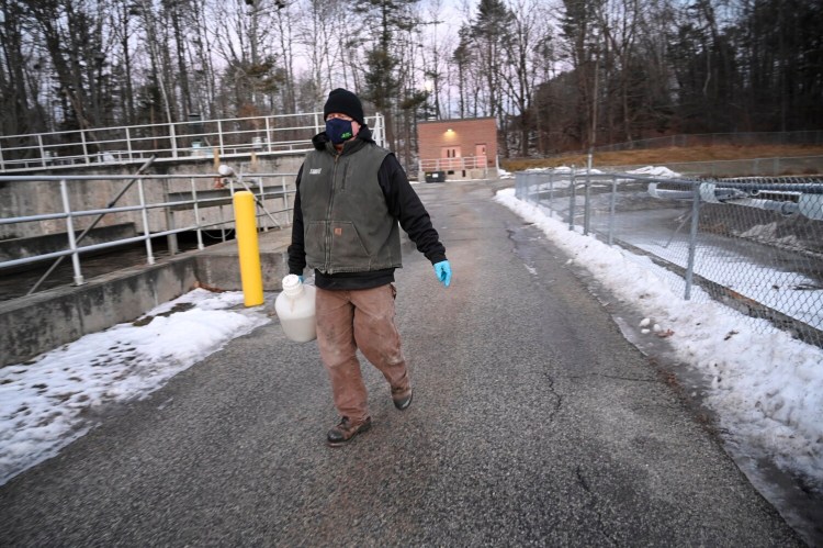 Brian Leighton, chief operator at the Yarmouth Wastewater Treatment Facility, carries a container with wastewater to be tested for COVID-19 on Tuesday.