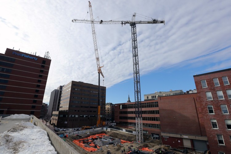 Workers erect a crane, right, with the use of a temporary, mobile crane at the construction site at the intersection of Federal and Temple streets on Thursday.