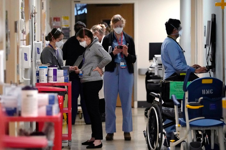 Medical workers fill a hallway in the acute care unit, where about half the patients are COVID-19 positive or in quarantine after exposure, of Harborview Medical Center, Friday in Seattle. 