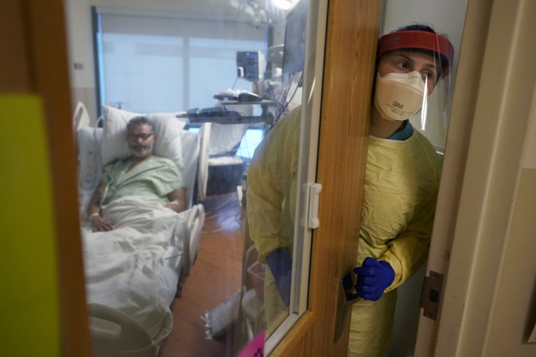 Registered nurse Rachel Chamberlin, of Cornish, N.H., steps out of an isolation room where Fred Rutherford, of Claremont, N.H., recovers from COVID-19 at Dartmouth-Hitchcock Medical Center in Lebanon, N.H., on Monday. Hospitals like this medical center, the largest in New Hampshire, are overflowing with severely ill, unvaccinated COVID-19 patients from northern New England. If he returns home, Rutherford said, he promises to get vaccinated and tell others to do so, too. 