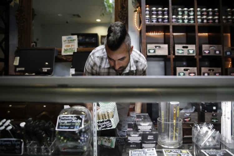 Jerred Kiloh, owner of the Higher Path medical marijuana dispensary, stocks shelves with with cannabis products in Los Angeles. Kiloh, who also heads the United Cannabis Business Association, a Los Angeles-based trade association said "No one is making money anywhere in the (legal) supply chain," he said, noting that his own sales have nosedived. 
