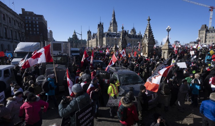 Protesters gather  around vehicles parked  in front of Parliament buildings in Ottawa on Saturday.

