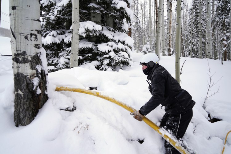 Ian Sidwell adjusts a hose at Vail Mountain Resort in December in Vail, Colo. Newer snowmaking technology is allowing ski areas to be more efficient with energy and water usage as climate change continues to threaten snowpack levels. 