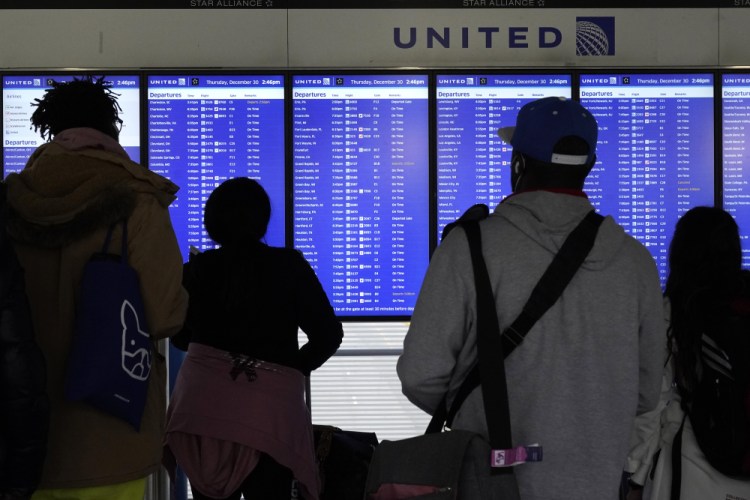 Travelers check departure screens for their flight status at O'Hare International Airport in Chicago, Thursday, Dec. 30, 2021.  