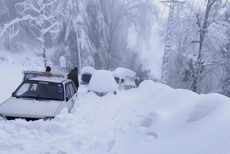 People walk past vehicles trapped in a heavy snowfall-hit area in Murree, some 28 miles north of the capital of Islamabad, Pakistan, Saturday. Temperatures fell to 17.6 Fahrenheit amid heavy snowfall at Pakistan's mountain resort town of Murree overnight, killing multiple people who were stuck in their vehicles, officials said Saturday.