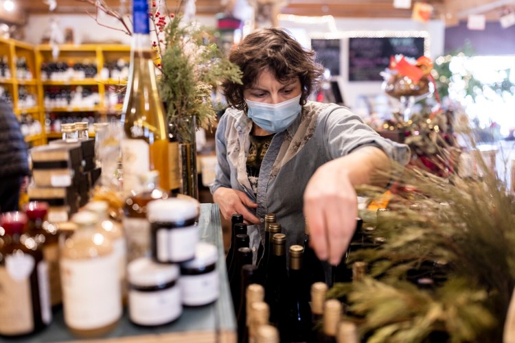 Nikaline Iacono, owner of Vessel and Vine, puts away wine at her Brunswick specialty shop on Friday. Inflation is at a 40-year high, and Iacono has been forced to raise prices and change her business model because of the pandemic.