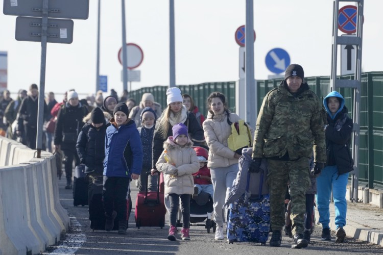 A Polish border guard assists refugees from Ukraine as they arrive to Poland at the Korczowa border crossing. 