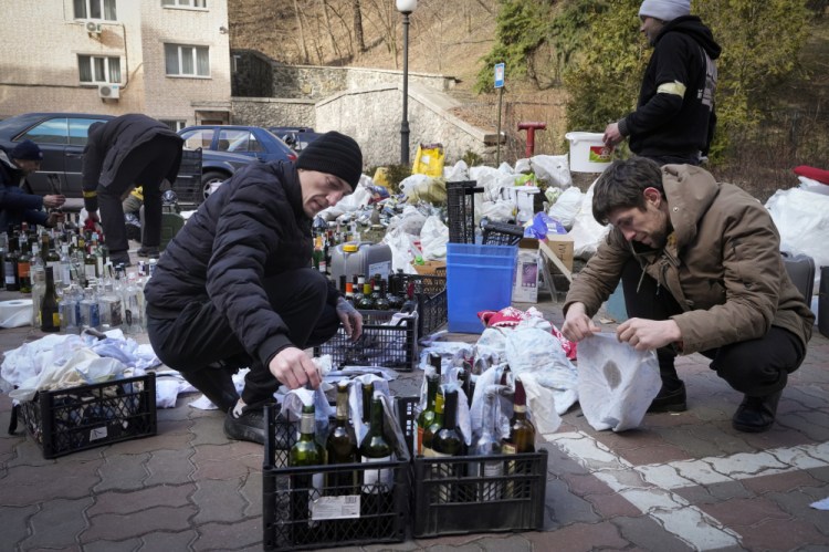 Members of civil defense prepare Molotov cocktails in a yard in Kyiv, Ukraine on Sunday. A Ukrainian official says street fighting has broken out in Ukraine's second-largest city of Kharkiv. 