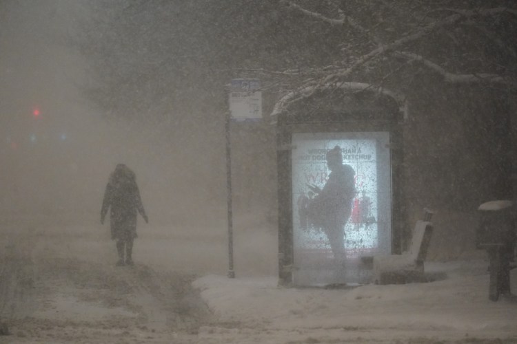 A woman walks to a bus shelter on Dr. Martin Luther King Drive as a man waits in the shelter during the pre-dawn hours on Wednesday in Chicago. A major winter storm with millions of Americans in its path brought a mix of rain, freezing rain and snow to the middle section of the United States.