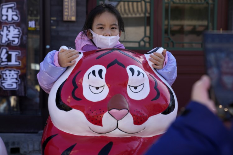A child holds on to the ears of a tiger sculpture on the first day of the Lunar Year of the Tiger in Beijing on Tuesday. 

