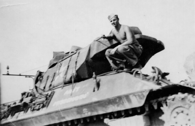 Donald Mead is shown posing on his tank, which was named “Ain’t Misbehavin” after a popular song of the day. Mead was  part of the Ghost Army WW II, a small and secret unit that used technology and ingenuity to deceive the German army and act as a decoy. 