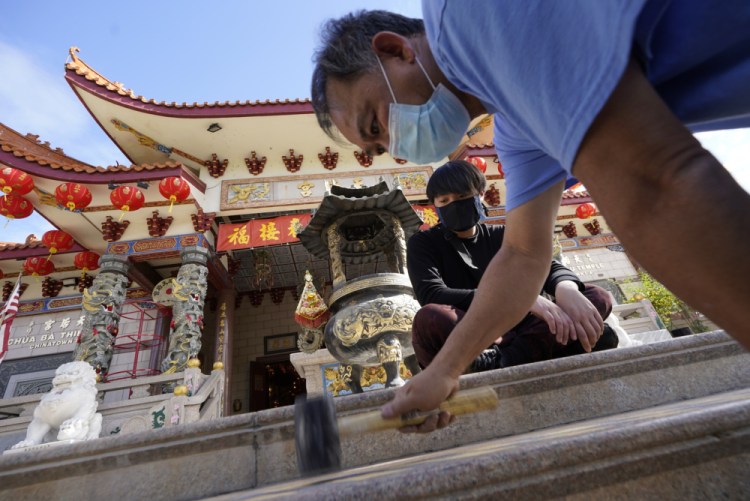 Volunteers Alex Koi, foreground, and his son Lipsun Koi, 20, help install anti-slip tape on the front steps of the Thien Hau Temple ahead of the crowds expected for the Lunar New Year of the Tiger celebrations in the Chinatown district of Los Angeles, Friday, Jan. 28, 2022. 
