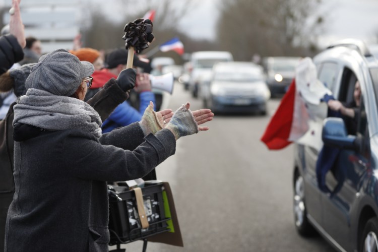 People applaud a convoy departing for Paris on Friday in Strasbourg, eastern France. Authorities in France and Belgium have banned road blockades threatened by groups organizing online against COVID-19 restrictions. The events are in part inspired by protesters in Canada. (AP Photo/Jean-Francois Badias)