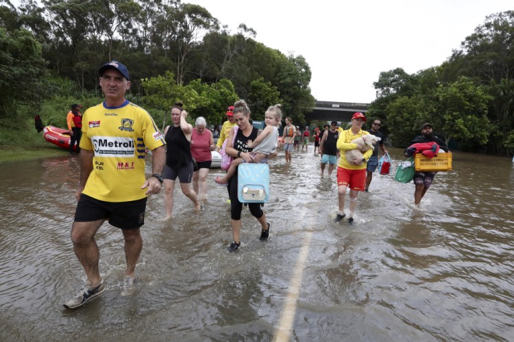 People wade through floodwater as they evacuate in Chinderah, Australia, on Tuesday.