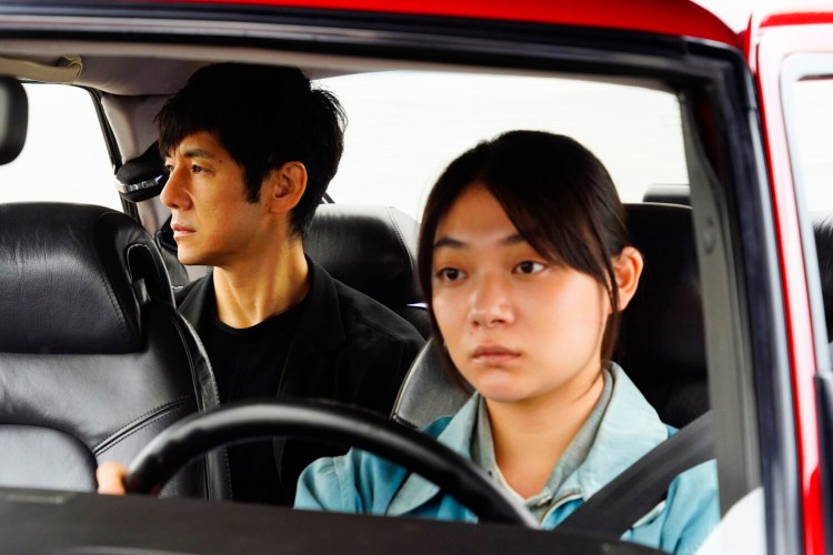 Hidetoshi Nishijima in the back seat and Tôko Miura behind the wheel in “Drive My Car.” MUST CREDIT: Janus Films