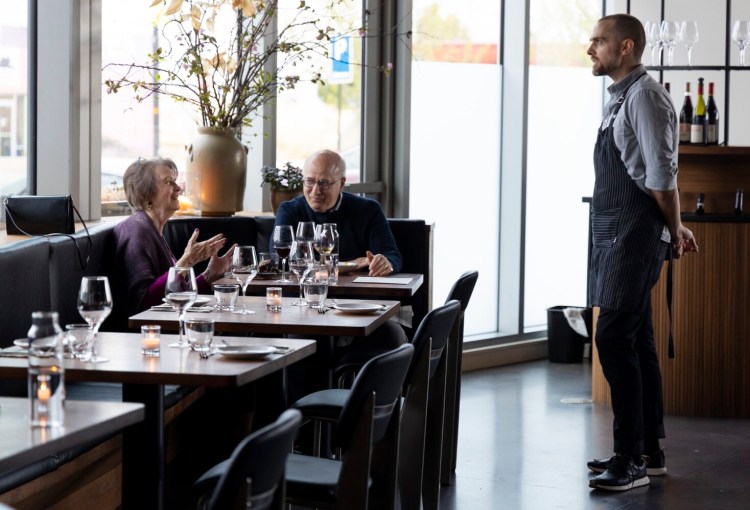 Server Justin Bourgoine chats with Sandra Lipsey and Bill Shain, of Falmouth, who were celebrating their 44th anniversary at Helm Oyster Bar & Bistro in late April.