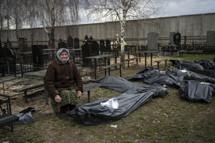 Nadiya Trubchaninova, 70, sits next to a plastic bag that contains the body of her son Vadym Trubchaninov, 48, who was killed by Russian soldiers in Bucha on March 30. 