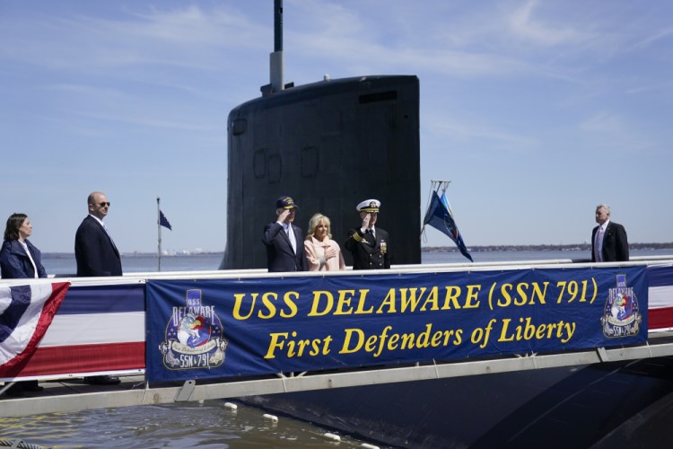 President Biden returns a salute as he stands with first lady Jill Biden and Cmdr. Matthew Horton before they board the USS Delaware, a Virginia-class fast-attack submarine, for a tour at the Port of Wilmington in Delaware on Saturday.
