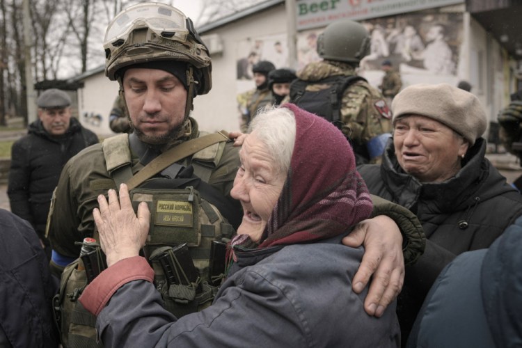 A woman hugs a Ukrainian serviceman after a convoy of military and aid vehicles arrived in the formerly Russian-occupied Kyiv suburb of Bucha, Ukraine, on Saturday. As Russian forces pull back from Ukraine's capital region, retreating troops are creating a "catastrophic" situation for civilians by leaving mines around homes, abandoned equipment and "even the bodies of those killed," President Volodymyr Zelenskyy warned Saturday.