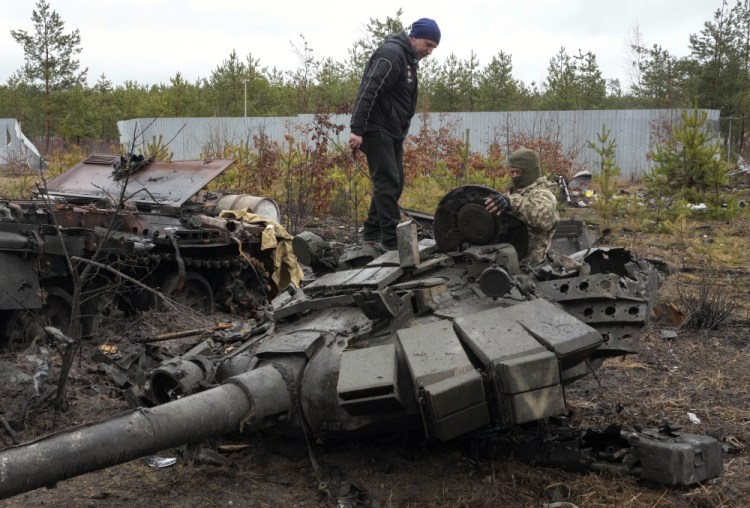 A Ukrainian soldier examines a destroyed Russian tank Saturday in the village of Dmytrivka close to Kyiv, Ukraine. At least ten Russian tanks were destroyed in the fighting two days ago in Dmytrivka. 