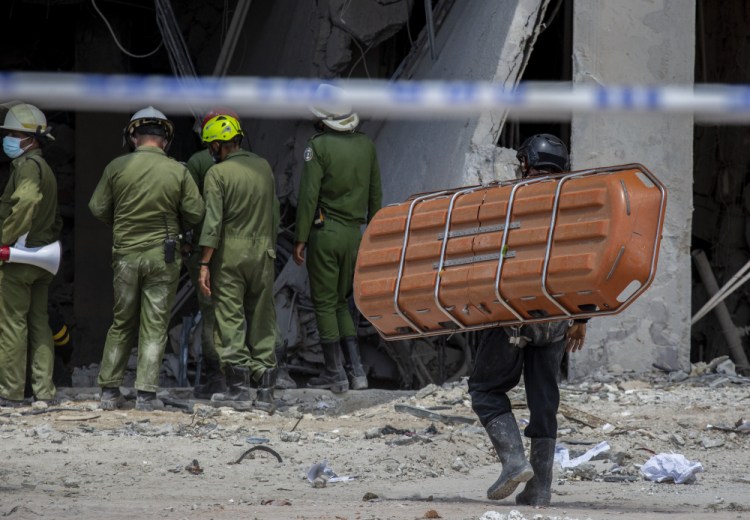 A member of the rescue team carries a stretcher Sunday to transport a body found in the rubble after an explosion destroyed the five-star Hotel Saratoga in Old Havana, Cuba. (AP Photo/Ismael Francisco)