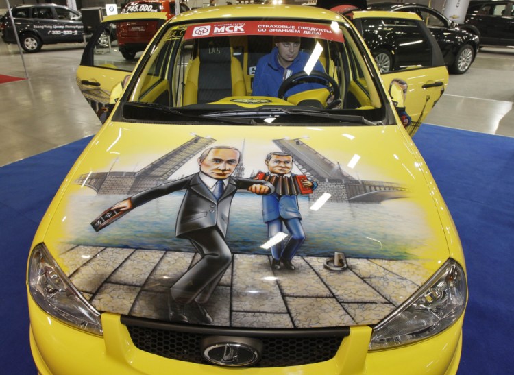 A man sits in a Russian-made Lada Kalina sports car with a depiction of Russian Prime Minister Vladimir Putin, left, and Russian President Dmitry Medvedev during an automotive exhibition in St. Petersburg, Russia, in 2011. 