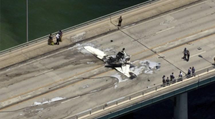 Emergency personnel respond to a small plane crash on a Miami bridge on Saturday. The plane struck an SUV and burst into flames. Six people were reported injured. (WSVN-TV via AP)