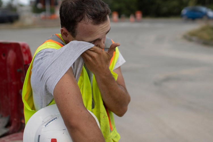 Trent Cullinan of Sargent Corporation wipes sweat from his face while taking a break from construction work in June 2021.