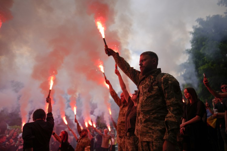 Soldiers hold flares as they attend the funeral Saturday of activist and soldier Roman Ratushnyi in Kyiv, Ukraine. Ratushnyi died in a battle near Izyum, where Russian and Ukrainian troops are fighting for control of the area.