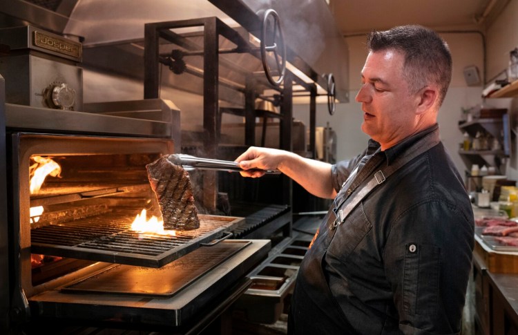 KENNEBUNKPORT, ME Ð June 29: Chef German Lucarelli flips a skirt steak on a Josper charcoal oven at The Lost Fire in Kennebunkport on Wednesday, June 29, 2022. Lucarelli heats the oven to about 700 degrees, which cooks the skirt steak in about two minutes. (Staff photo by Gregory Rec/Staff Photographer)