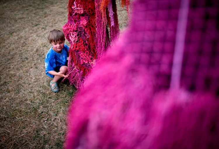 Henry Atwood, 5, of Portland checks out a temporary art installation titled "Beneath the Forest, Beneath the Sea" at Payson Park on Thursday. The three large scultpures by artist Pamela Moulton were made with more than 10 tons of repurposed and derelict fishing equipment, known as ghost gear.