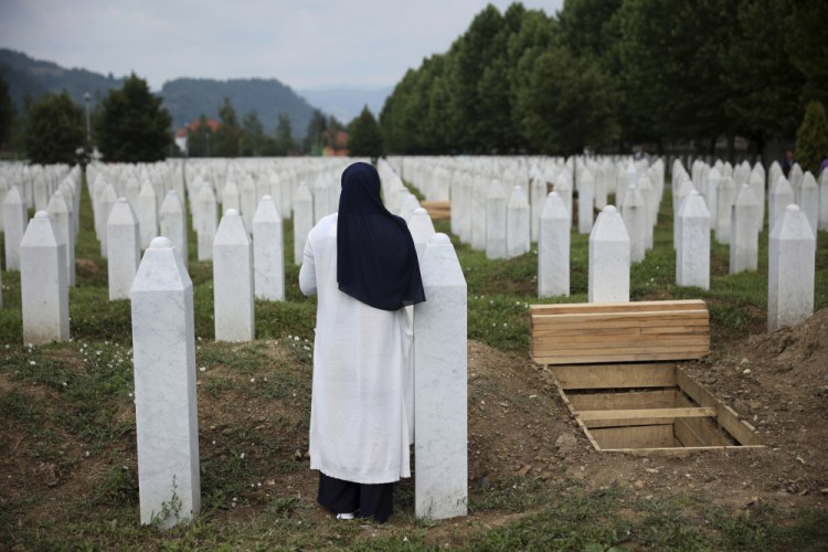 A woman prays near the grave of a family member in the Memorial center in Potocari, Bosnia, on Friday. More than 8,000 male relatives of Srebrenica women were killed in the 1995 Srebrenica massacre.