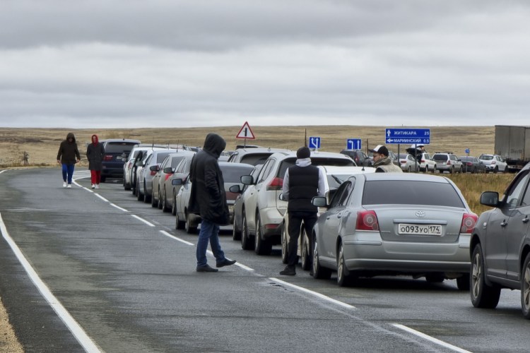 People walk next to cars queuing to cross the border into Kazakhstan at the Mariinsky border crossing, about 250 miles south of Chelyabinsk, Russia, on Tuesday. Officials say about 98,000 Russians have crossed into Kazakhstan in the week since President Vladimir Putin announced a partial mobilization of reservists to fight in Ukraine. 