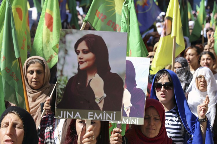 Kurdish women hold portraits of Mahsa Amini during a protest condemning her death in Qamishli, Syria, on Monday. 