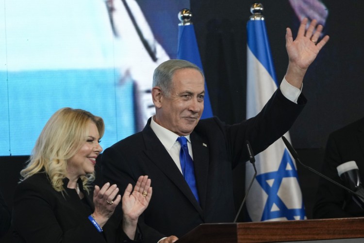 Benjamin Netanyahu, former Israeli Prime Minister and the head of Likud party, accompanied by his wife Sara waves to his supporters after first exit poll results for the Israeli Parliamentary election at his party's headquarters Wednesday in Jerusalem.