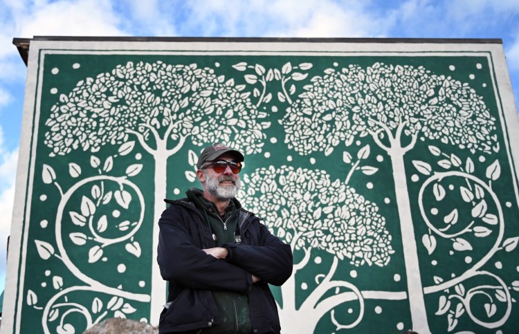  Portland artist Pat Corrigan in front of his recent mural at the former Greyhound Bus terminal. Corrigan is a muralist in some ways despite himself. 